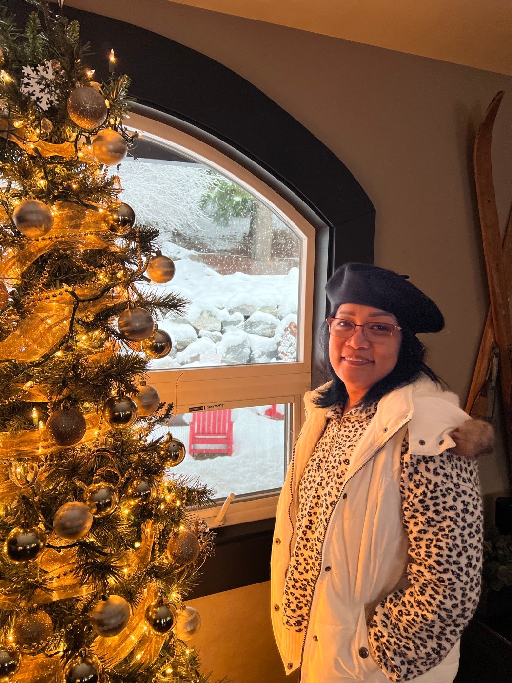 Kathy, the maker behind Nursed Petals, smiling next to a decorated Christmas tree